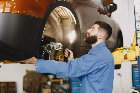 Certified car mechanic in Kenosha, WI performing a brake repair inspection on a vehicle rotor.